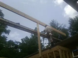Carpenter setting a ridge beam over a new addition frame — Ice Dam Removal by Roofing Brothers in Fort Gratiot