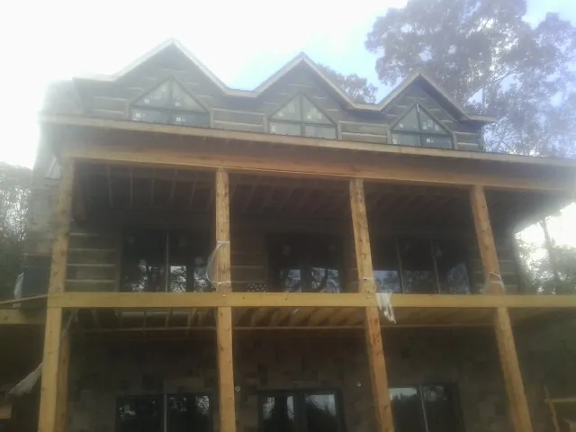 Dormers and porch framing on a large log home under construction — Roof Coating work by our crew in Fort Gratiot