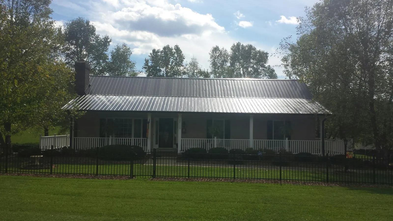 Gray metal roof on a brick ranch with a full width front porch — Gutter Guard Installation work by our crew in Fort Gratiot